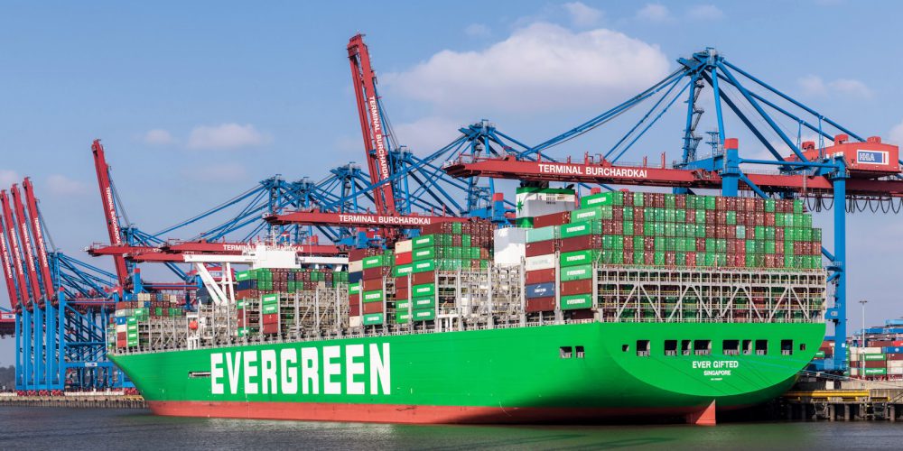 A large green cargo ship docked at a dock